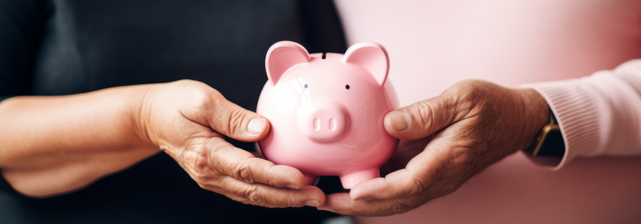 Retirement dreams with senior couple's hands holding a pink piggy bank symbolizing their shared commitment to saving for future and retirement pension