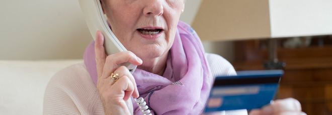 older woman on phone while reading credit card information